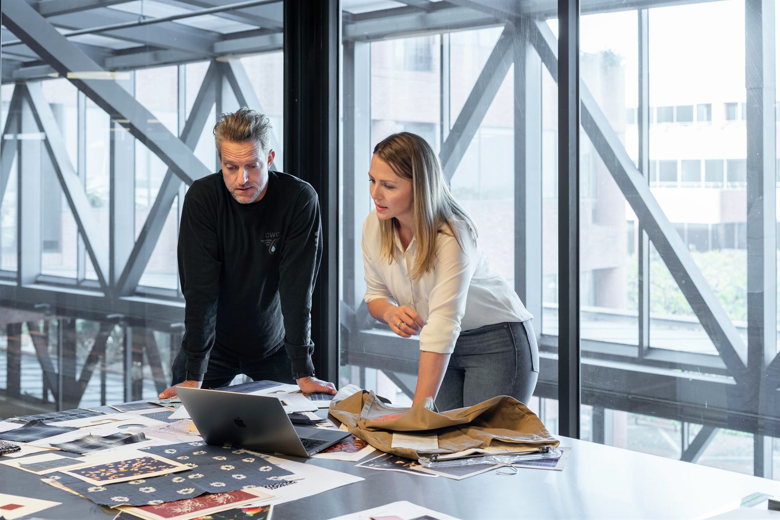 Two consultants reviewing printed plans at a table
